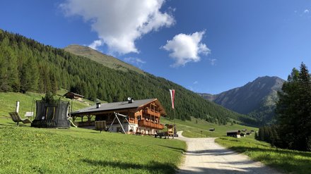 Baita alpina in montagna Baita alpina su un prato verde con vista sulle montagne e il cielo azzurro.